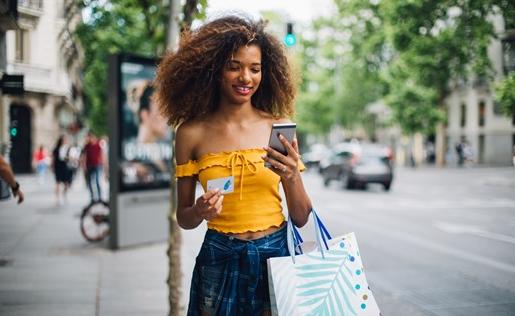 A woman with her phone and a bag of shopping items